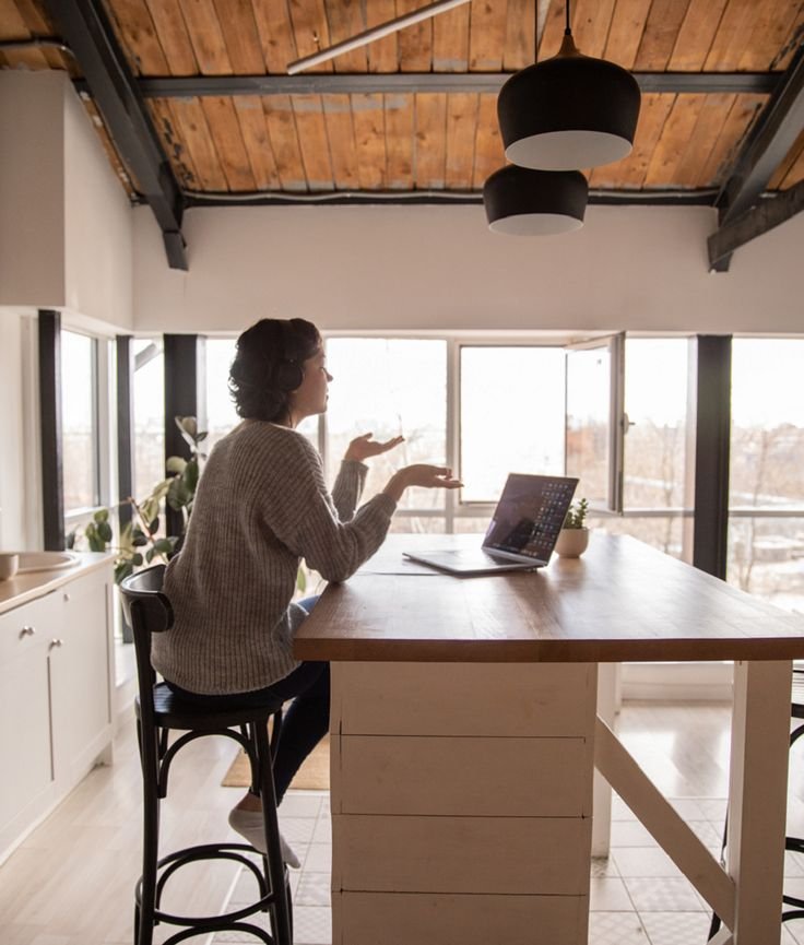 Mujer sentada haciendo videollamada a traves de una netbook